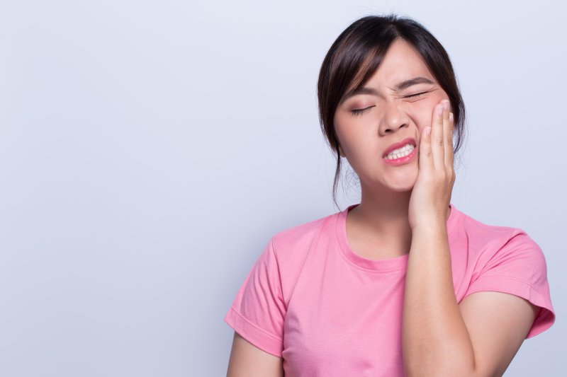 person with dental emergency holding face in pain