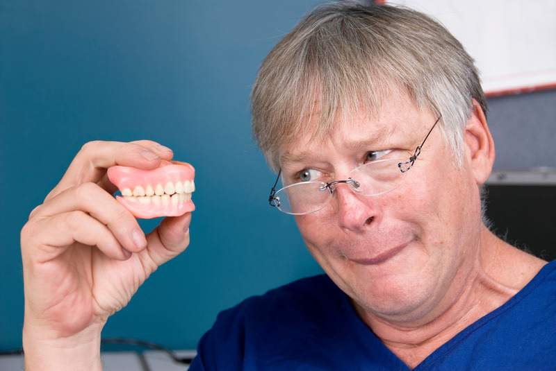 Older patient holding their dentures